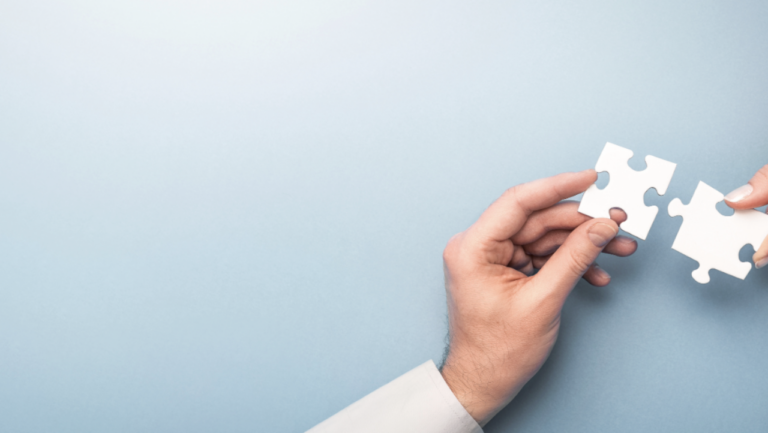 Light blue background with two hands holding a jigsaw puzzle piece each.